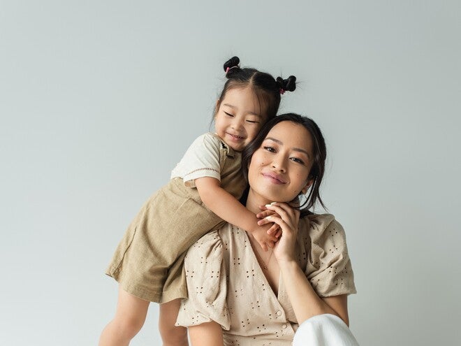 Photo: seated woman with child hugging her shoulders