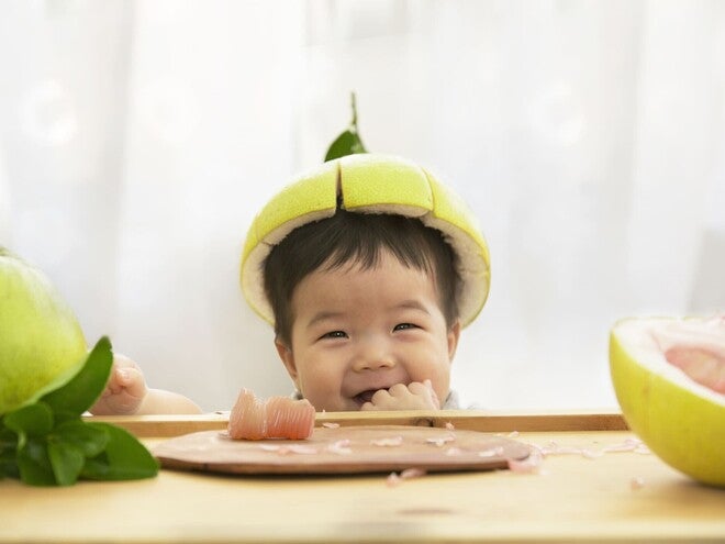 Photograph: green pear with cut top on a chocolate puddle, grapefruit half nearby