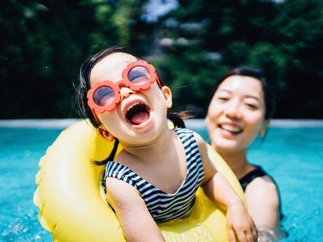 Photo: a child and mother in pool; one in striped suit sits in yellow swim ring
